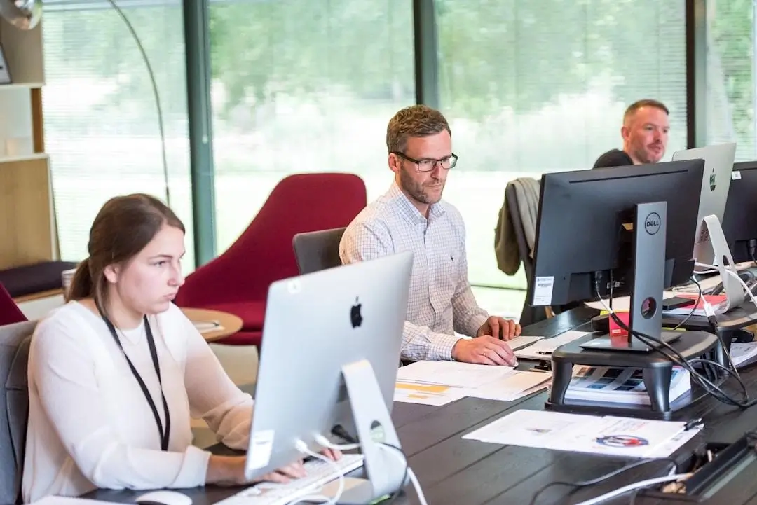 Employees working together at a desk in a professional office environment.